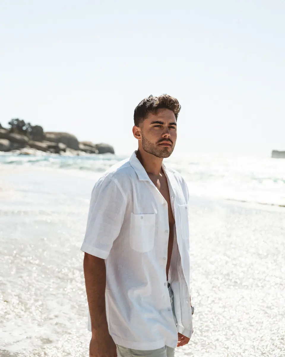 Homme en chemise blanche ouverte au bord de la mer